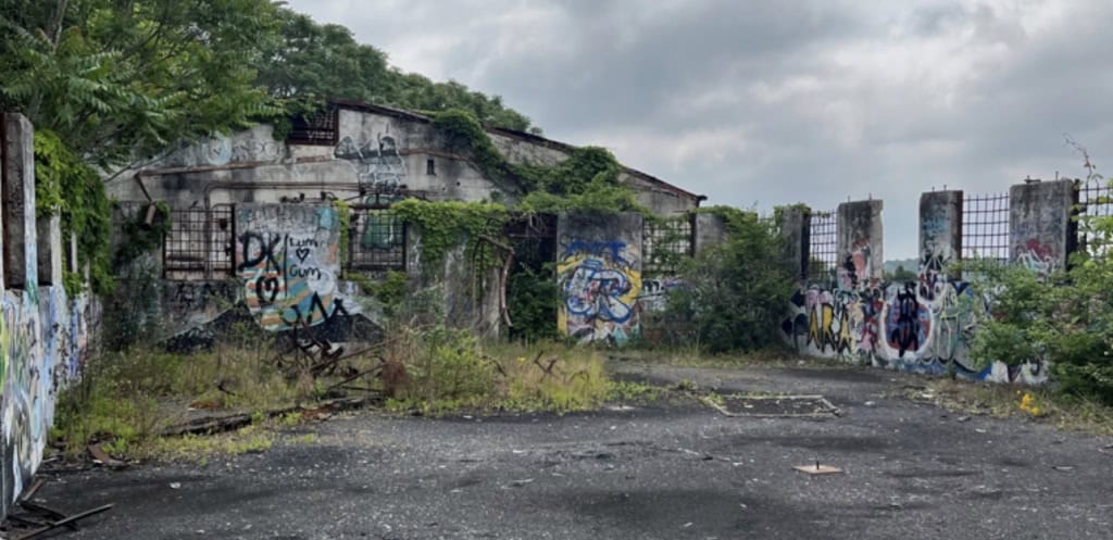Abandoned, graffiti-covered prison yard with overgrown vegetation and rusted fences, highlighting the urgent need for criminal justice reform and prisoner rights awareness in Georgia.